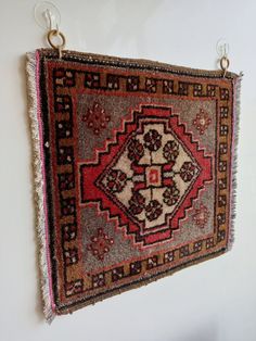 an old rug hanging on the wall with some hooks attached to it's sides