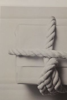 a rope wrapped in white paper on top of a wall next to a box with a knot