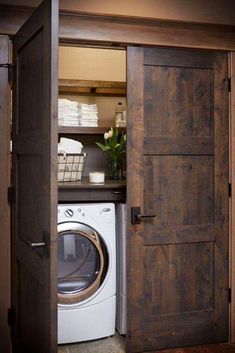 a washer and dryer in a small room with wooden doors leading to the bathroom