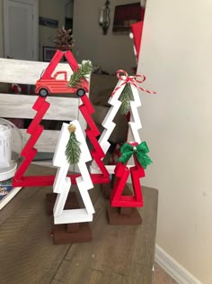 two small wooden christmas trees sitting on top of a table next to a red truck