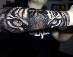 a man's arm with a tiger face tattooed on the inside of his arm