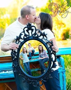 a man and woman kissing in front of a blue bench with an ornate frame on it