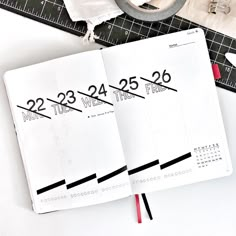 an open planner book sitting on top of a table next to a pair of scissors