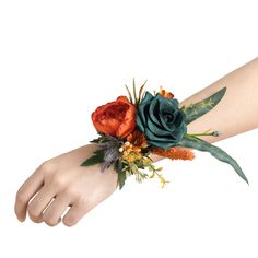 a woman's arm with an orange and green flower arrangement on top of it