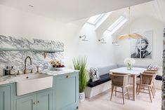 a kitchen with green cabinets and marble counter tops, along with a dining room table