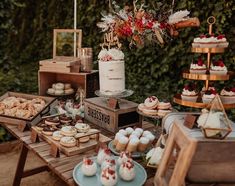 a table topped with cakes and desserts next to a wooden box filled with cupcakes