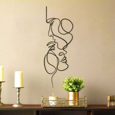 a metal sculpture is on the wall next to candles and a vase with flowers in it