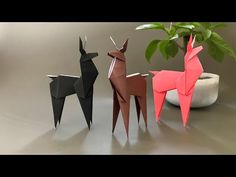 three origami deer standing next to a potted plant