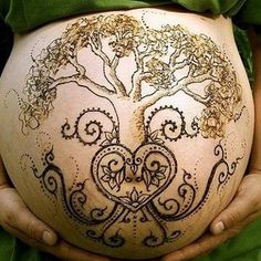 a pregnant woman is holding her belly with intricate designs on it's side, while wearing a green dress