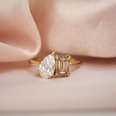 a close up of a ring with a diamond in it on a pink satin background