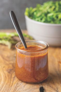 a jar filled with sauce sitting on top of a wooden table