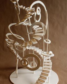 a sculpture made out of books and paper on top of a white stand with spirals