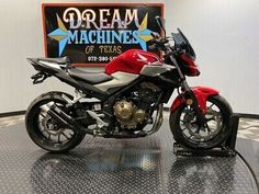 a red and black motorcycle on display in a room with a sign behind it that says dream machines of texas