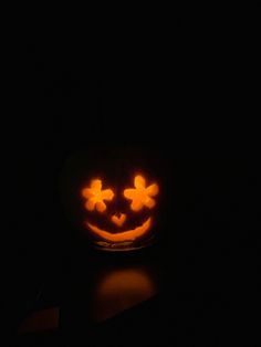 a pumpkin with two faces carved into it's face, lit up in the dark