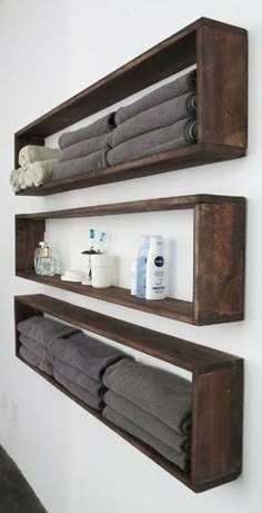 two wooden shelves holding towels and other bathroom items