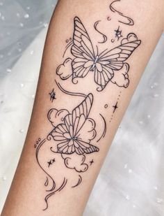 a woman's arm with two butterflies on it and stars in the sky above