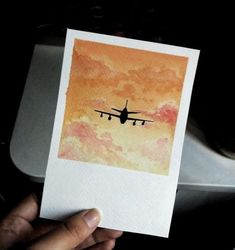 a person holding up a card with an airplane painted on it