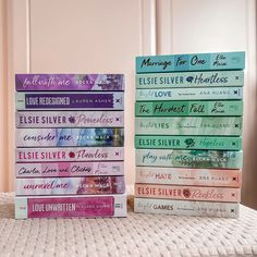 a stack of books sitting on top of a bed next to each other in front of a window