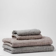 three folded linens stacked on top of each other in various colors and patterns, one is light gray