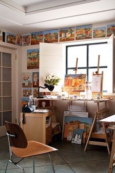an artist's studio with paintings on the wall and desks in front of it