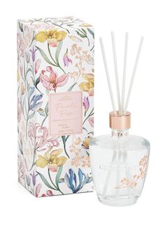 a white box with a pink and yellow flowered diffuser next to an empty bottle