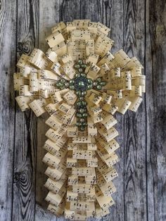 a cross made out of sheet music on top of wooden planks with musical notes attached to it