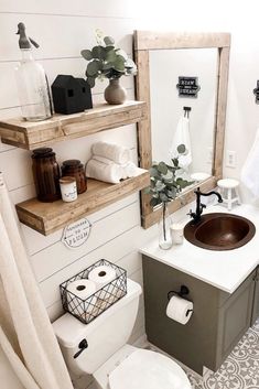 a white toilet sitting next to a bathroom sink under a mirror above a wooden shelf