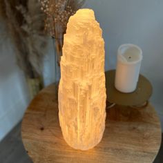 a large crystal piece sitting on top of a wooden table next to a white candle