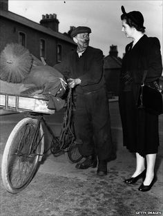 an old man and woman standing next to a baby carriage