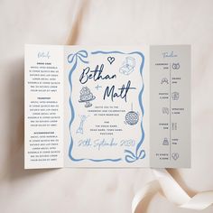 a blue and white wedding program on top of a sheet of paper next to a ribbon