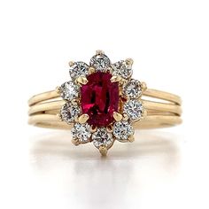 a gold ring with a red stone surrounded by white diamonds