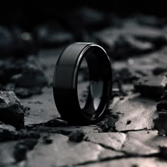 a black ring sitting on top of a rock covered ground with rocks in the background