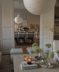 a living room filled with furniture next to a dining room table and white walls in the background