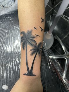 a palm tree and birds tattoo on the arm