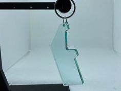 a glass keychain hanging from a metal hook on a white background with an object in the foreground