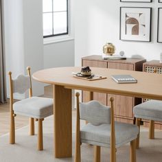 a wooden table with chairs and a remote control on top of it in front of a window