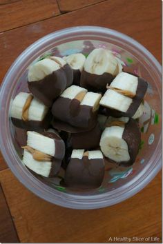 a bowl filled with chocolate covered bananas on top of a wooden table