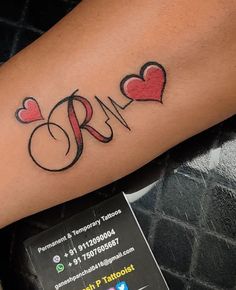 a person with a tattoo on their arm that has hearts and the letter r in it