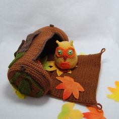 a knitted owl is sitting in a crochet bag with leaves around it