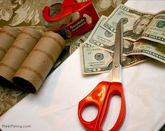 a pair of red scissors sitting on top of a table next to rolled up money