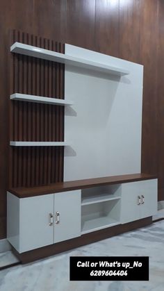 a white entertainment center with wooden shelves and drawers on the side, against a wall