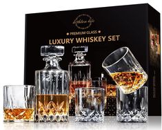 an assortment of whiskey glasses and decanters in front of a black box with gold lettering