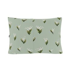 a green pillow with white flowers on the front and back of it, against a light blue background