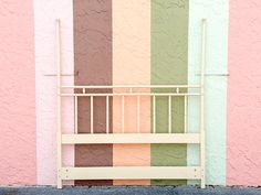 a white bench sitting in front of a multicolored wall