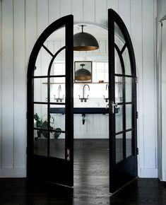 an open door leading into a kitchen with black doors and glass windows on the inside