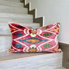 a pink pillow sitting on top of a wooden bench next to some stairs with white railings