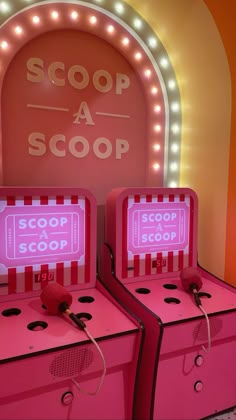 two pink arcade machines sitting in front of a neon sign that says scoop a scoop