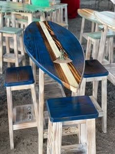 a surfboard table and stools are set up in an outdoor cafe setting with chairs around it