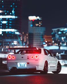 a white car parked in front of a city at night