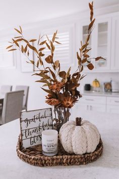 a basket filled with pumpkins sitting on top of a counter next to a candle